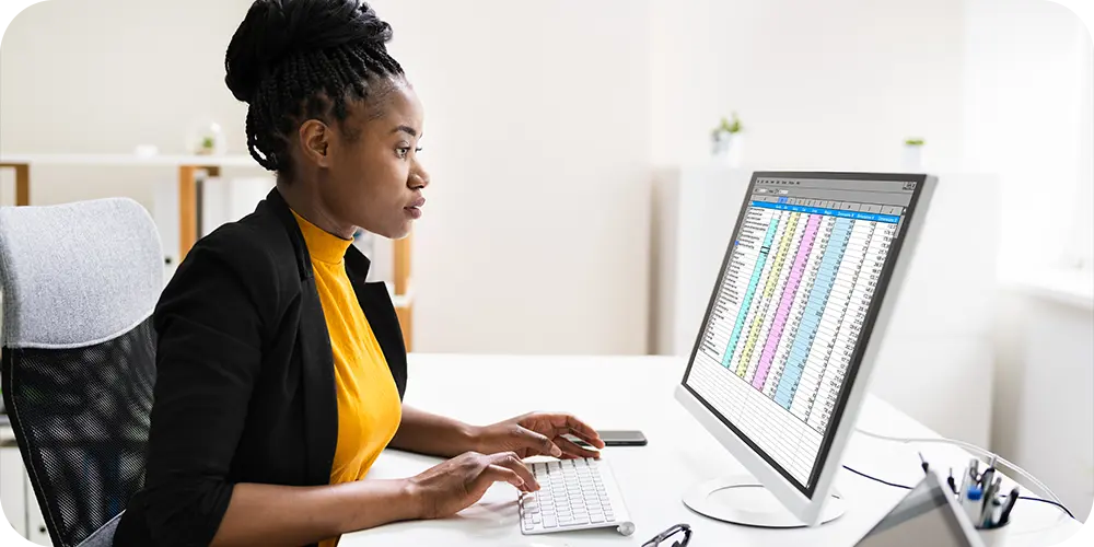 Professional reviewing spreadsheets and data on computer.